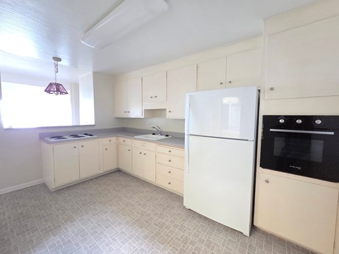 A kitchen with white appliances and cabinets.