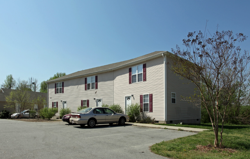 A silver car is parked in front of a two-story building.