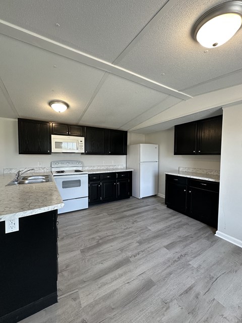 A kitchen with black cabinets and white appliances.