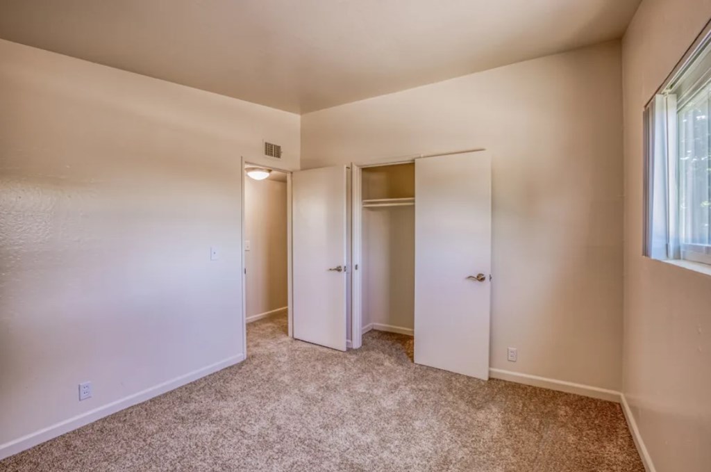 A room with carpeted floor and two doors.