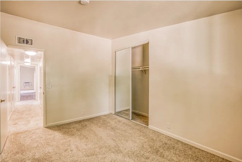 A room with a carpeted floor and a door leading to another room.