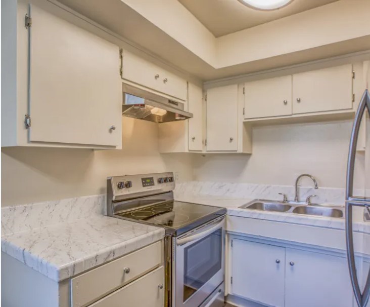 A kitchen with white cabinets and a marble countertop.