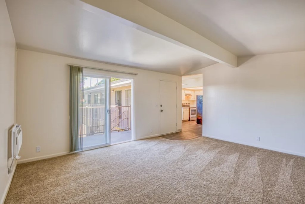 A spacious room with a carpeted floor and a slanted ceiling.