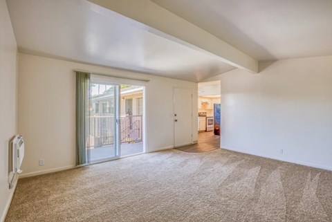 A spacious room with a carpeted floor and a slanted ceiling.