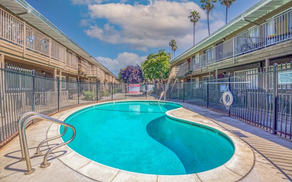 A swimming pool in a residential area surrounded by a fence.