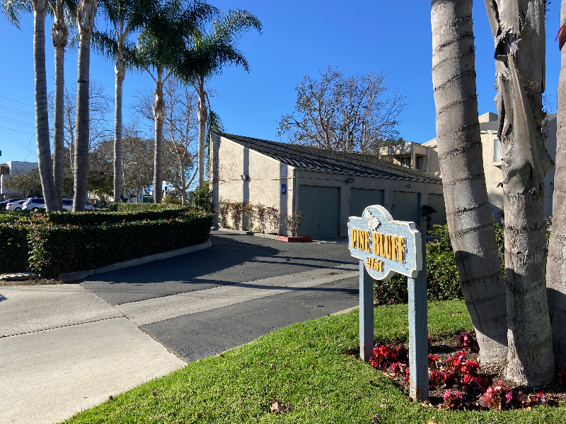 A sign that says "Pine Hollow" is in front of a building and some trees.