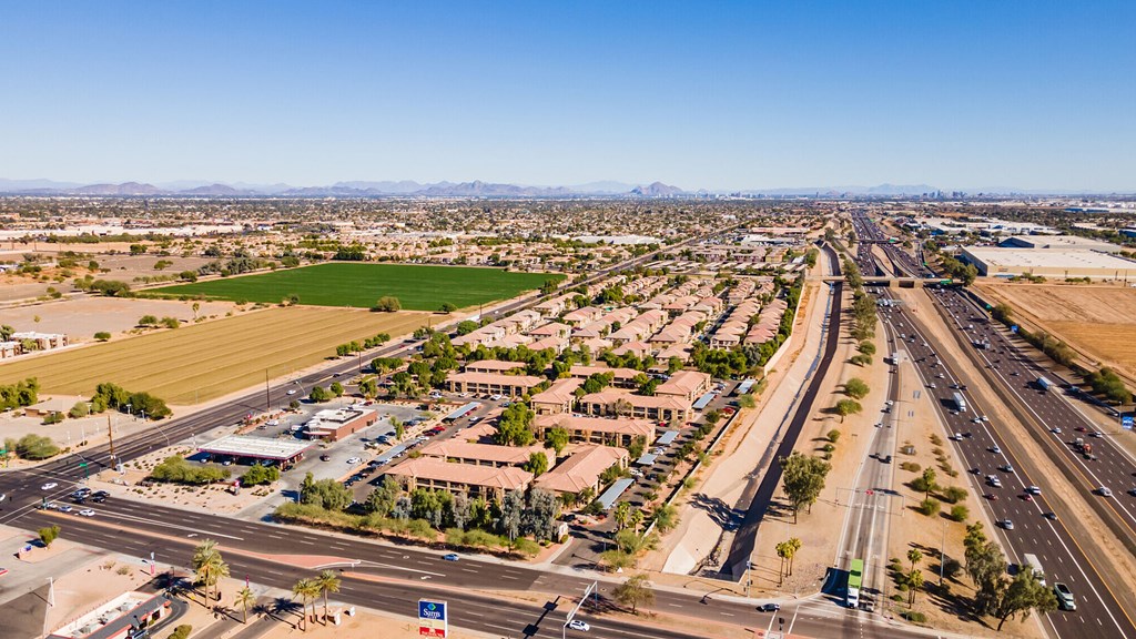 A highway interchange with buildings and green fields in the foreground.
