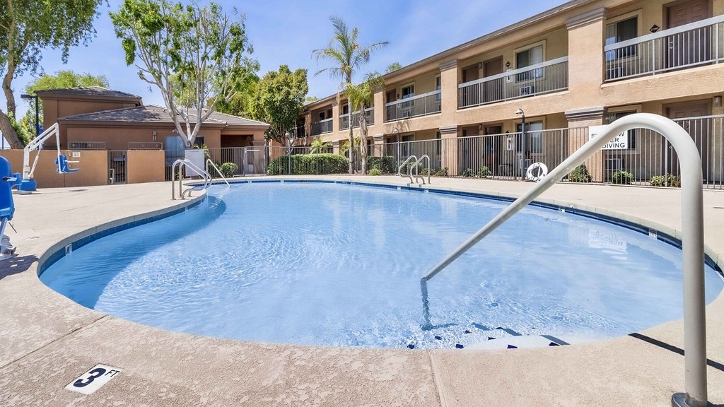A swimming pool in front of a building with a blue sky in the background.