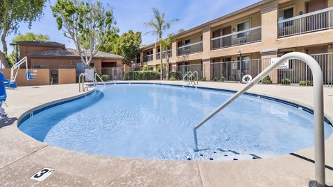 A swimming pool in front of a building with a blue sky in the background.