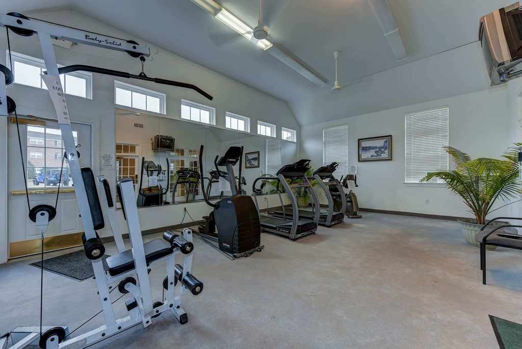 A gym with a variety of equipment including treadmills, weights, and exercise machines.