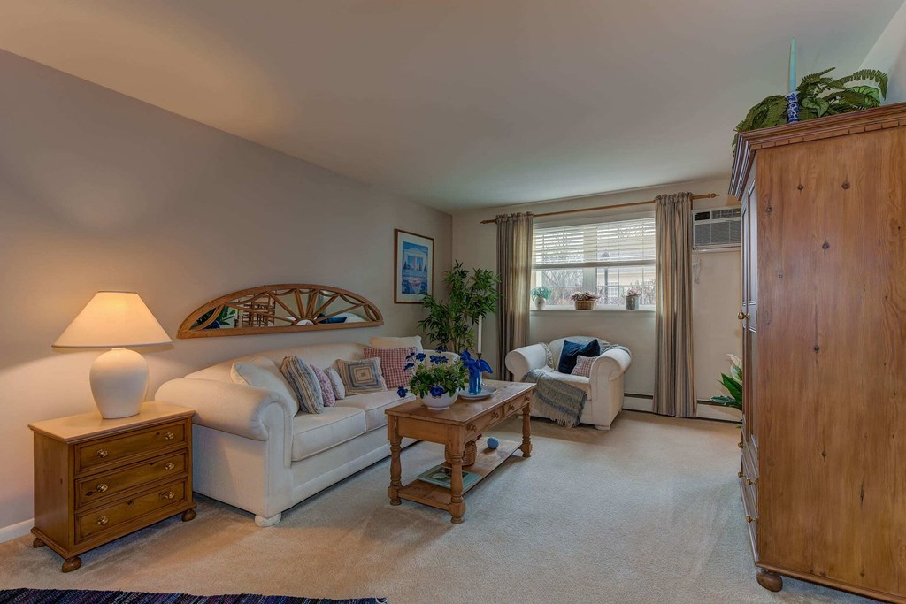A living room with a white couch, a wooden side table, and a wooden cabinet.