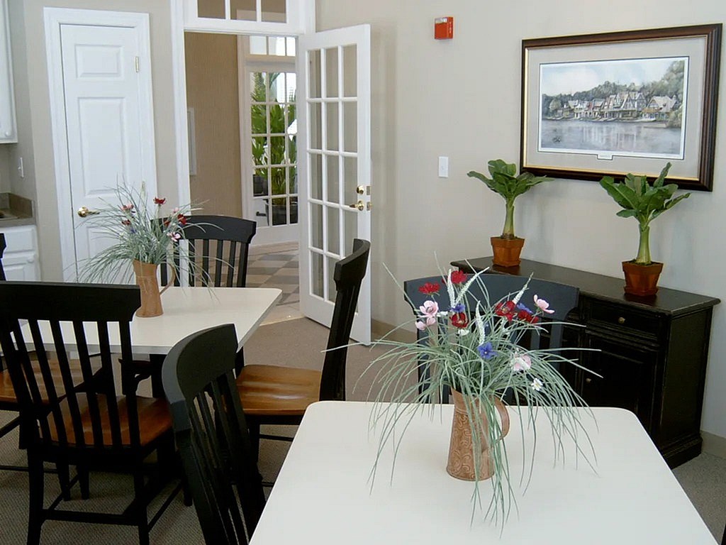 A dining room with a table, chairs and a vase of flowers.