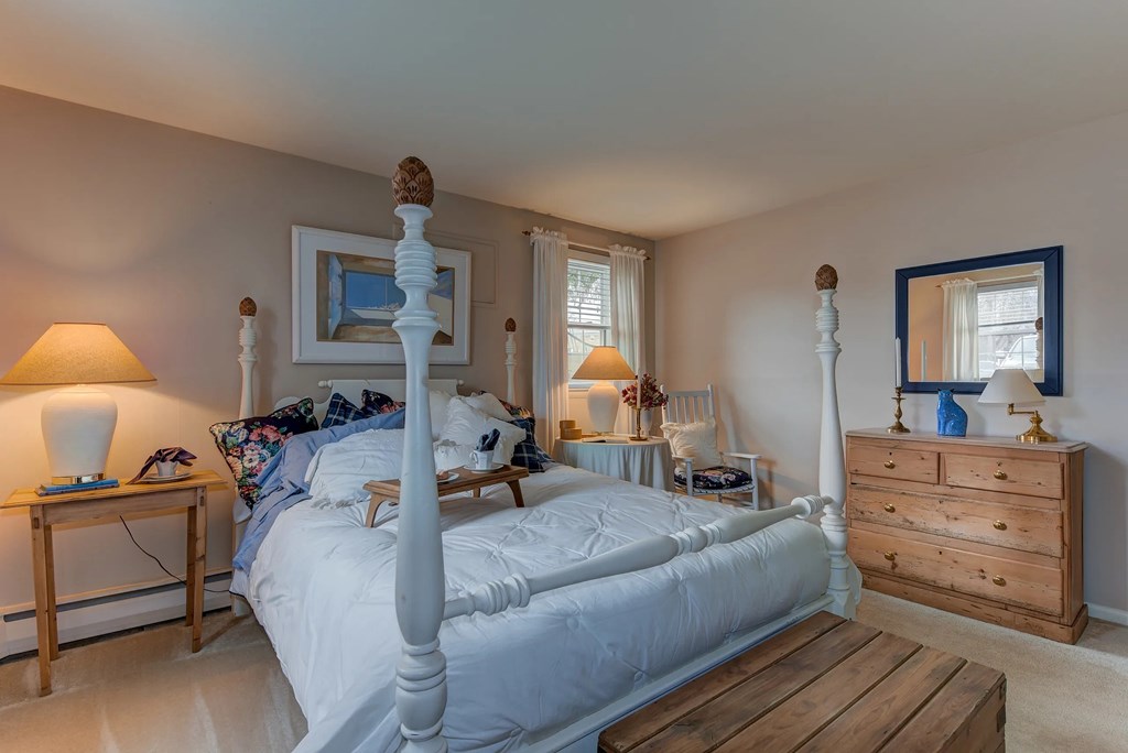A bedroom with a large bed, a wooden nightstand, and a wooden bench.