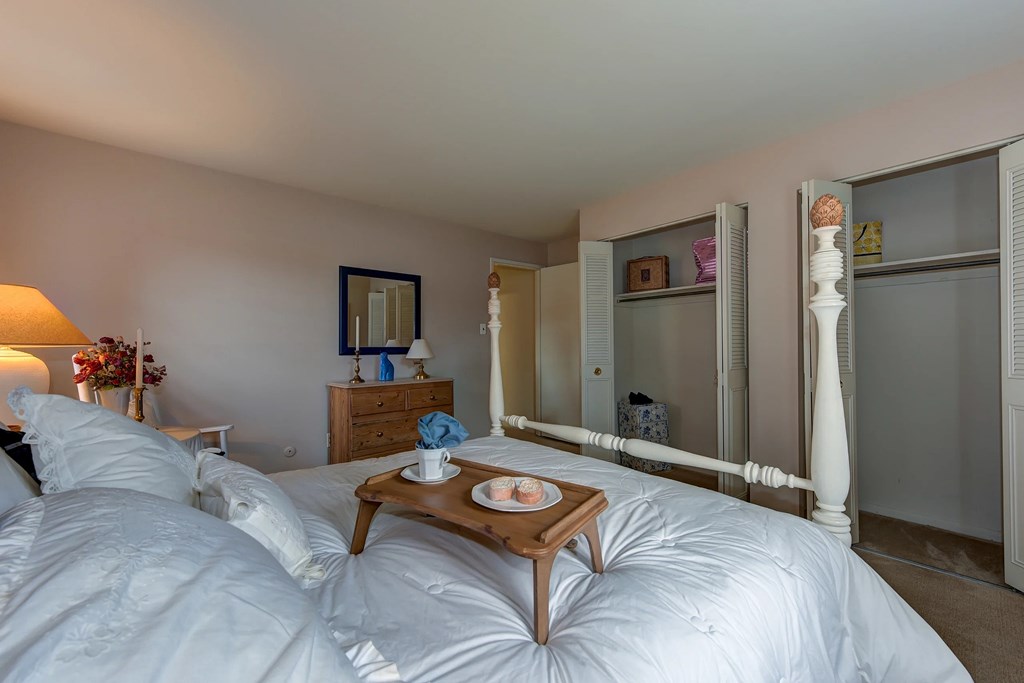 A bedroom with a large bed and a nightstand with a lamp.