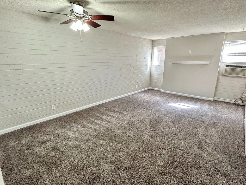 A room with a ceiling fan and carpeted floor.