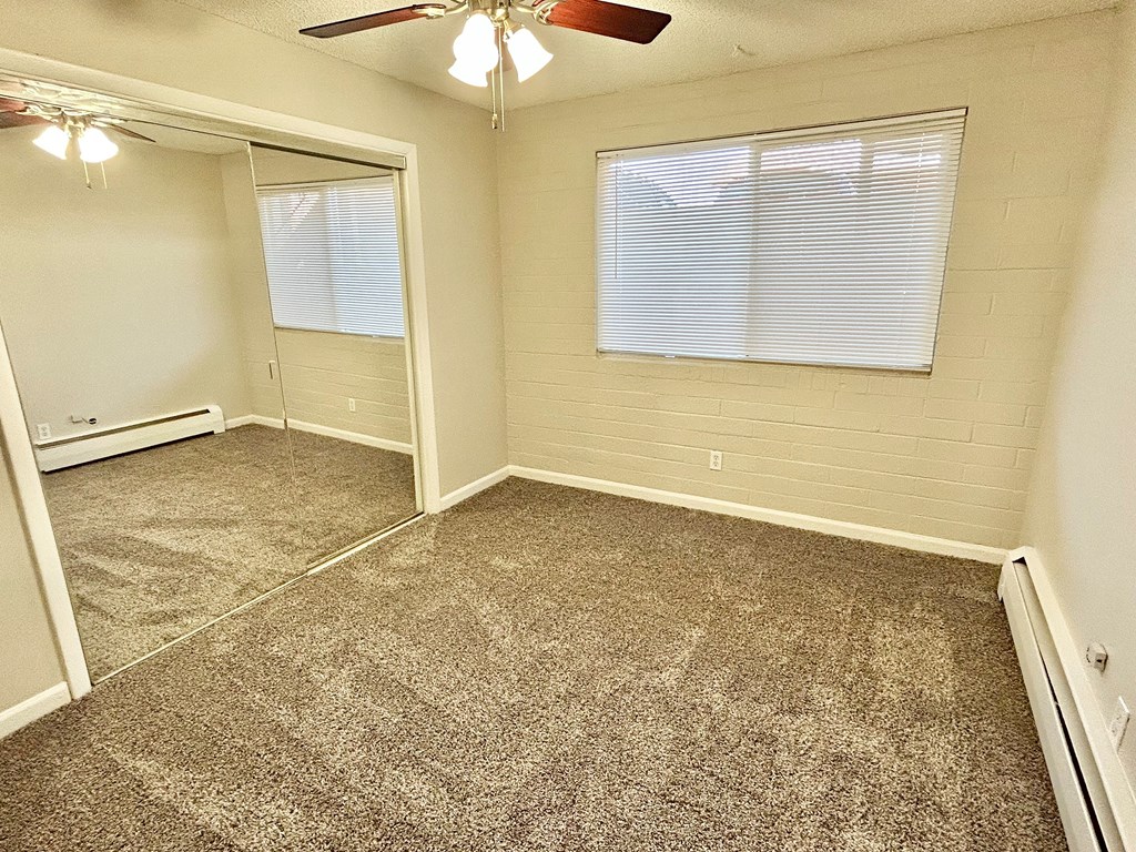 A room with a ceiling fan and carpeted floor.