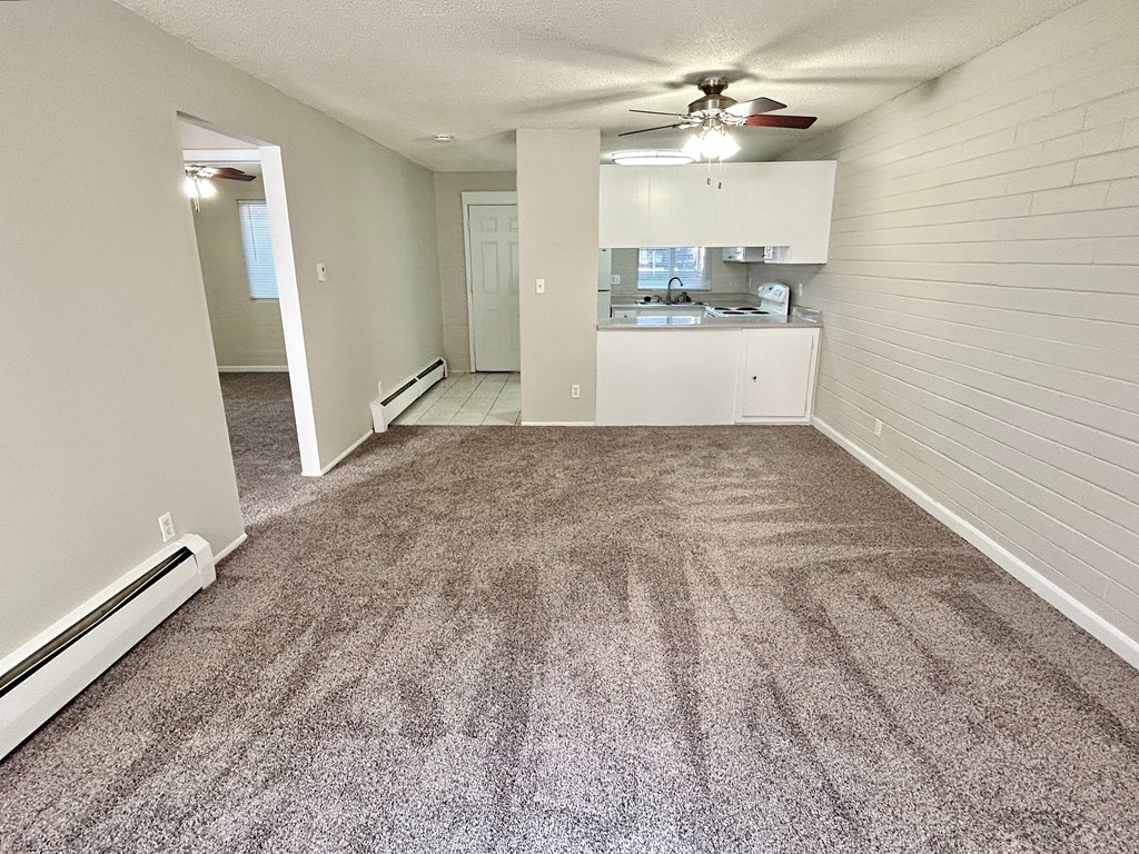 A room with a carpeted floor and a ceiling fan.