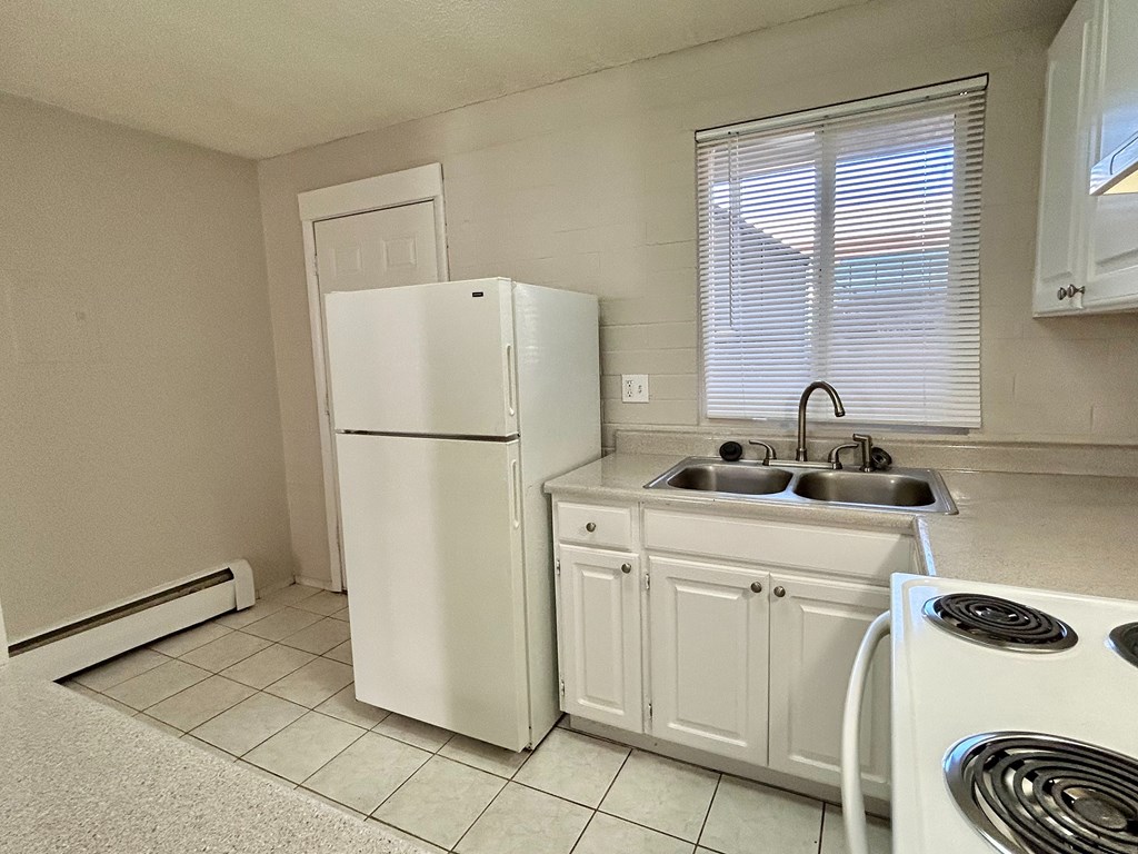 A white kitchen with a refrigerator, sink, and dishwasher.