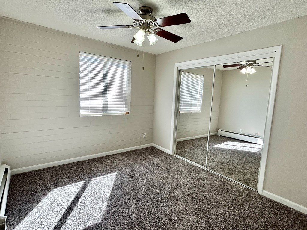 A room with a ceiling fan and a large mirror.