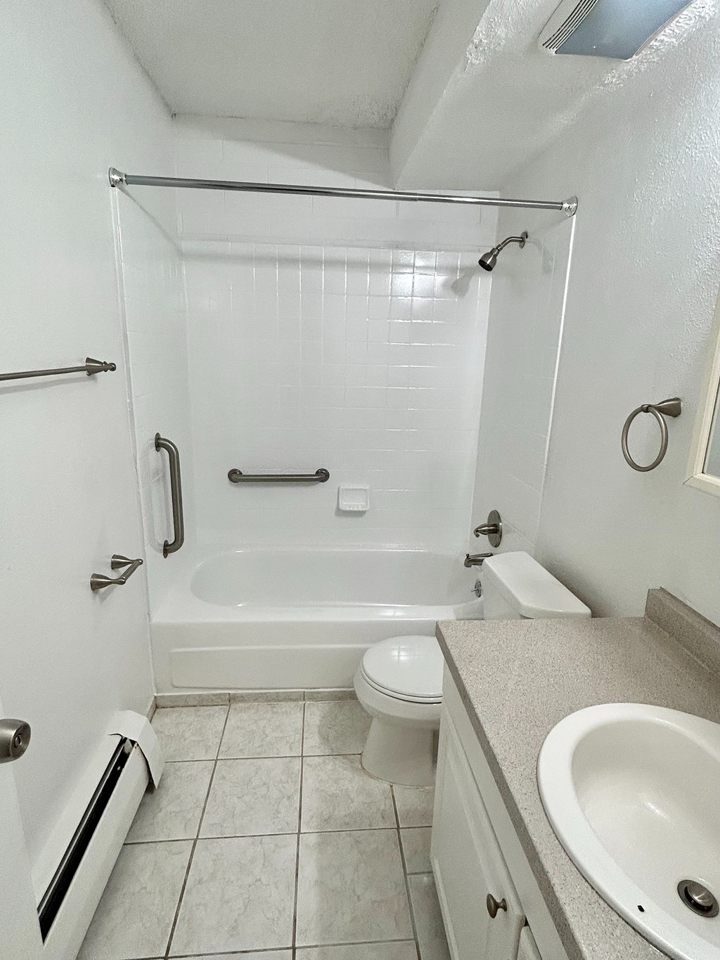 A white bathroom with a toilet, sink, and shower.