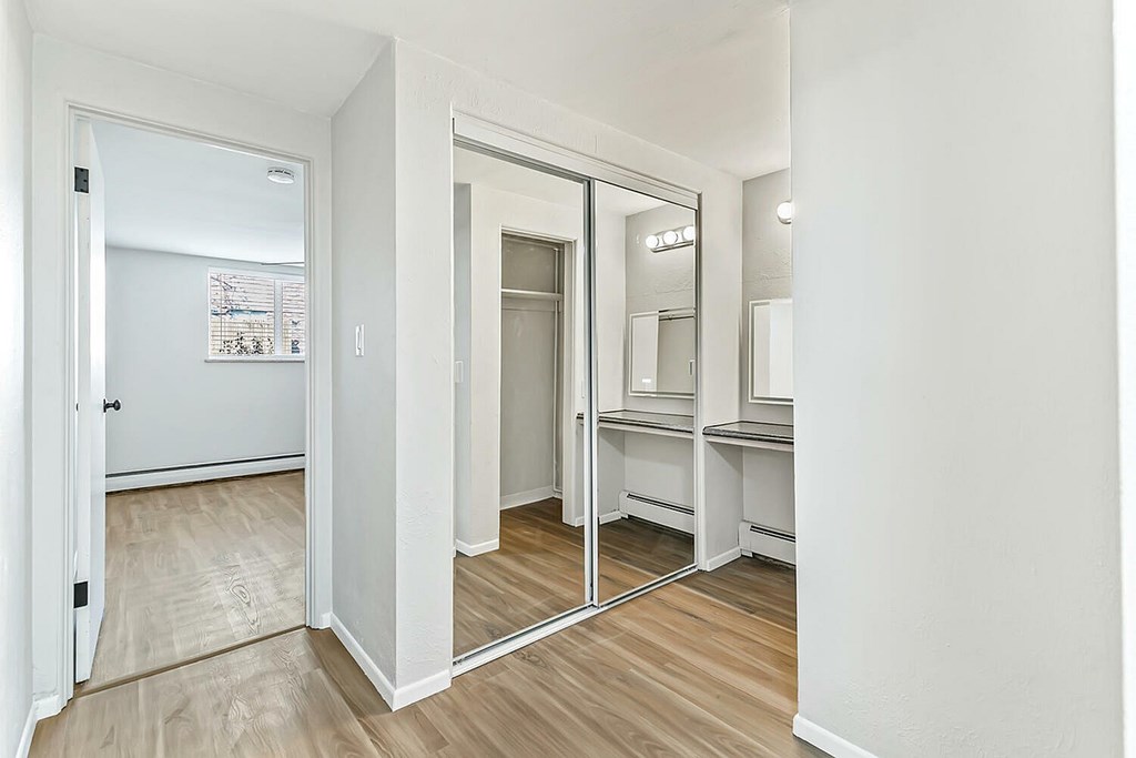 A white room with a mirror and a fridge.