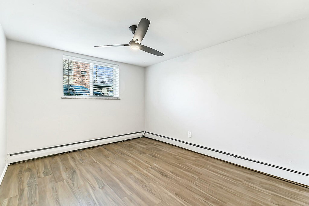 A room with a ceiling fan and a window with blinds.