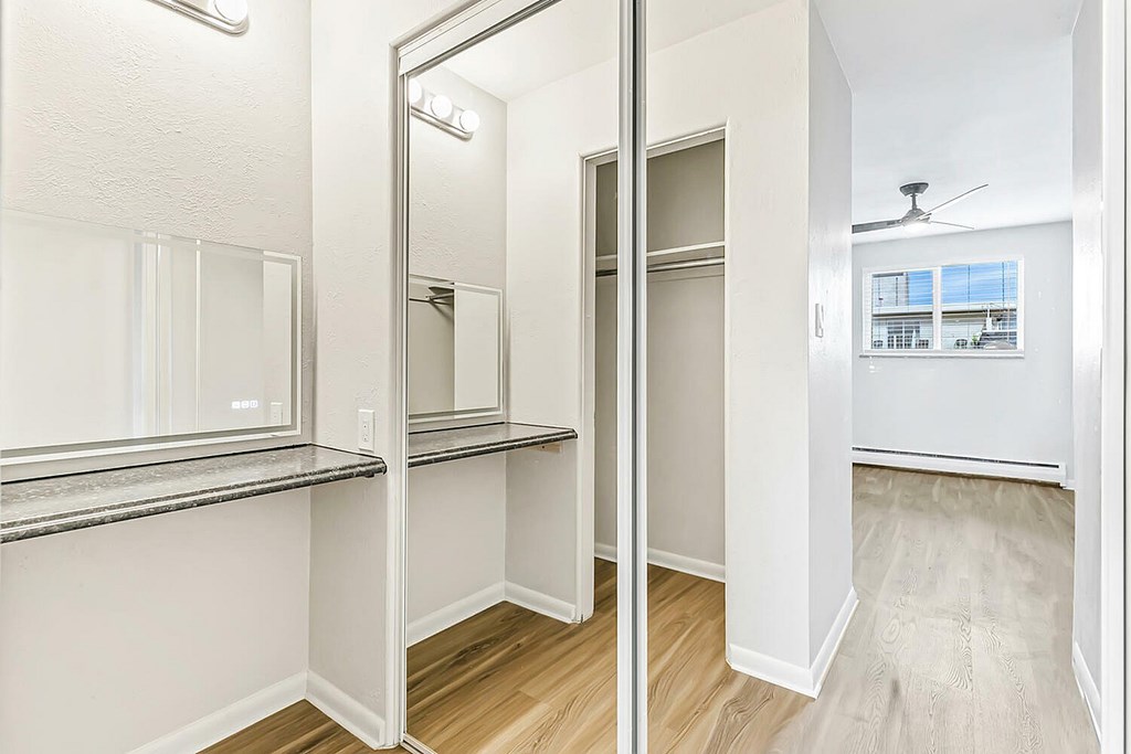 A white hallway with a mirror and a fan.