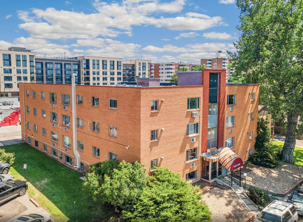 A red brick building with a red awning sits in front of a parking lot.