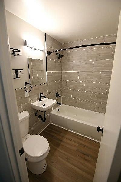 A white toilet is in a small bathroom with a white sink and a white bathtub.