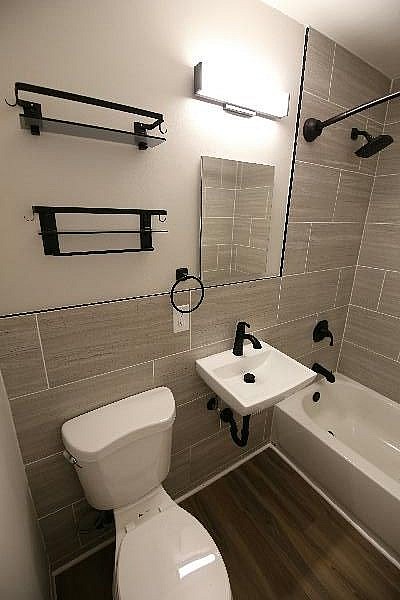 A white toilet is in a small bathroom with a white sink and a white bathtub.