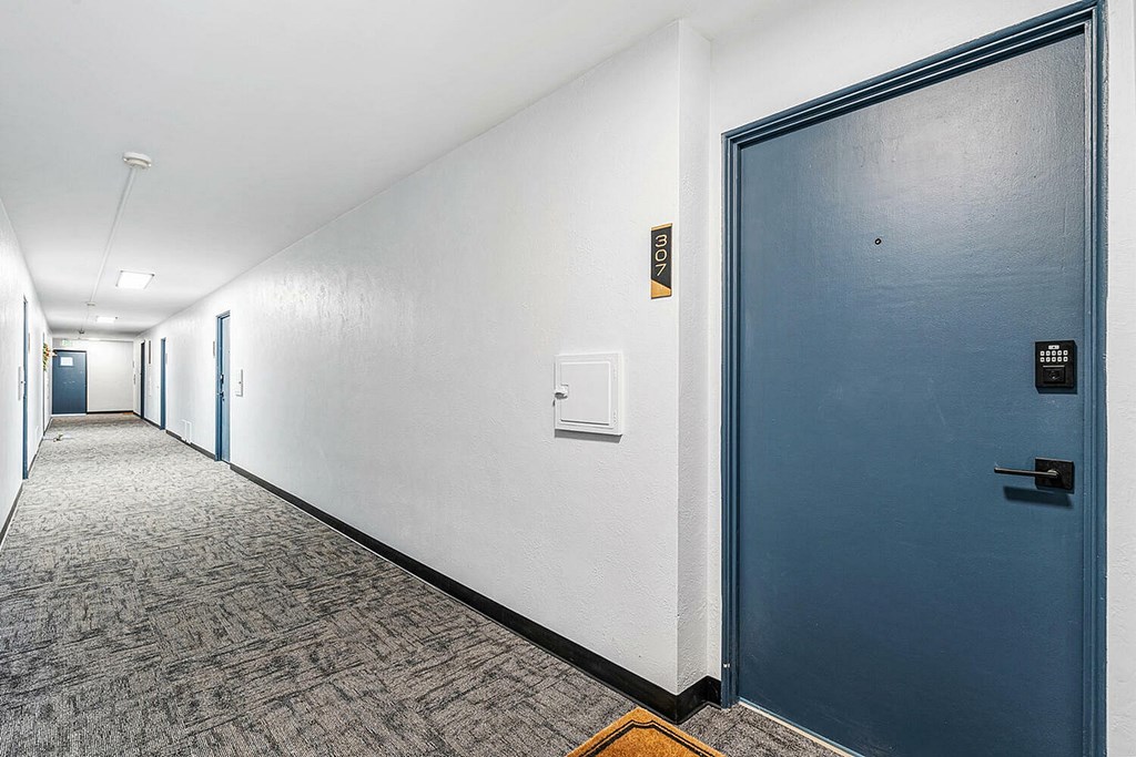 A long hallway with a blue door on the right.