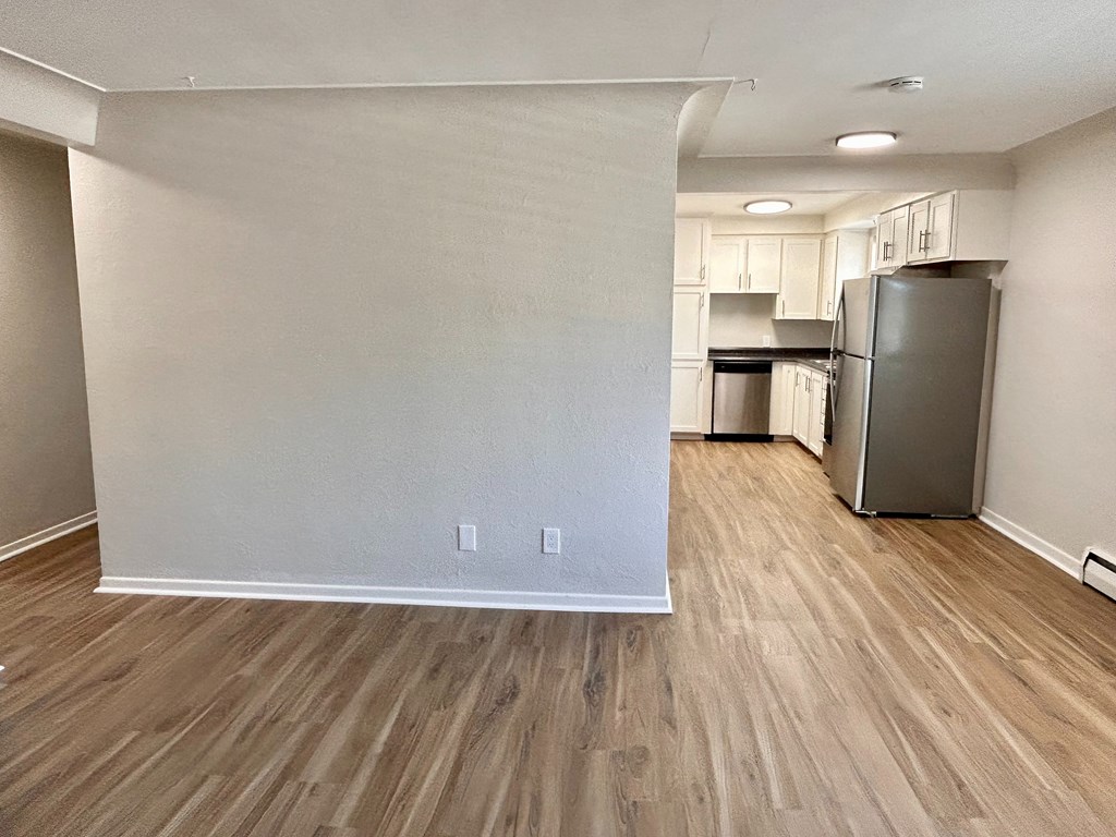 A kitchen area with a refrigerator, cabinets, and a countertop.