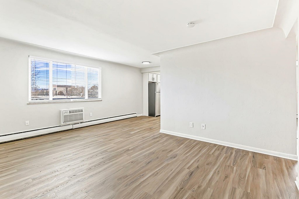 A room with wooden flooring and a window with blinds.