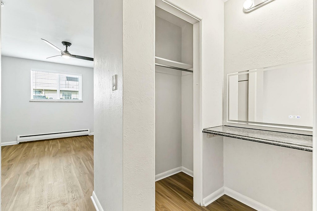 A white room with a window and a fan on the ceiling.