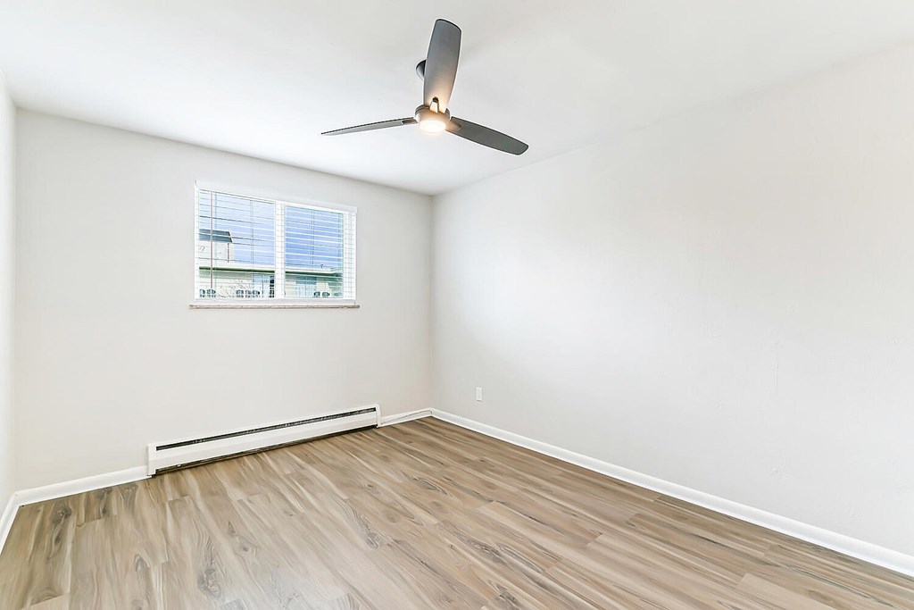 A room with a ceiling fan and a window with blinds.