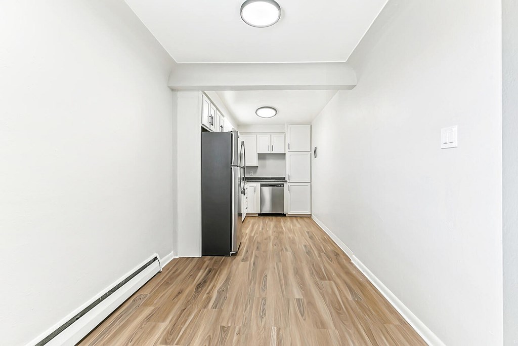 A kitchen with a black refrigerator and wooden floors.