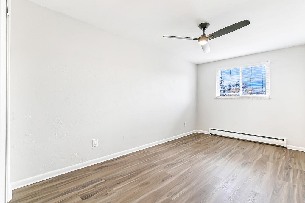 A room with a ceiling fan and a window with blinds.