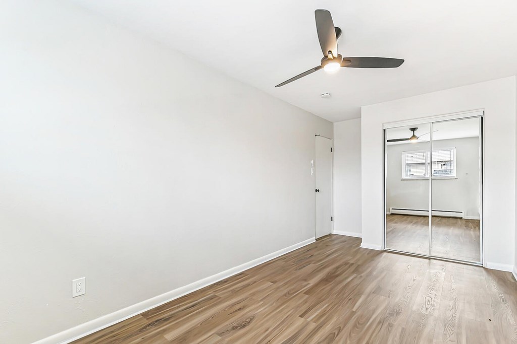 A room with a ceiling fan and wooden flooring.