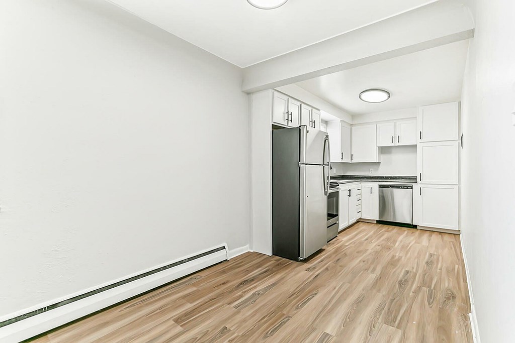 A kitchen with a refrigerator, cabinets, and a countertop.