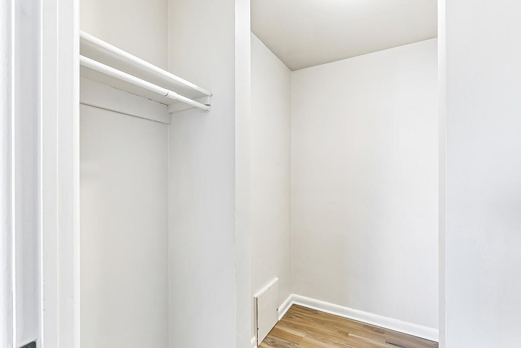 A white closet with a white door and a white shelf.