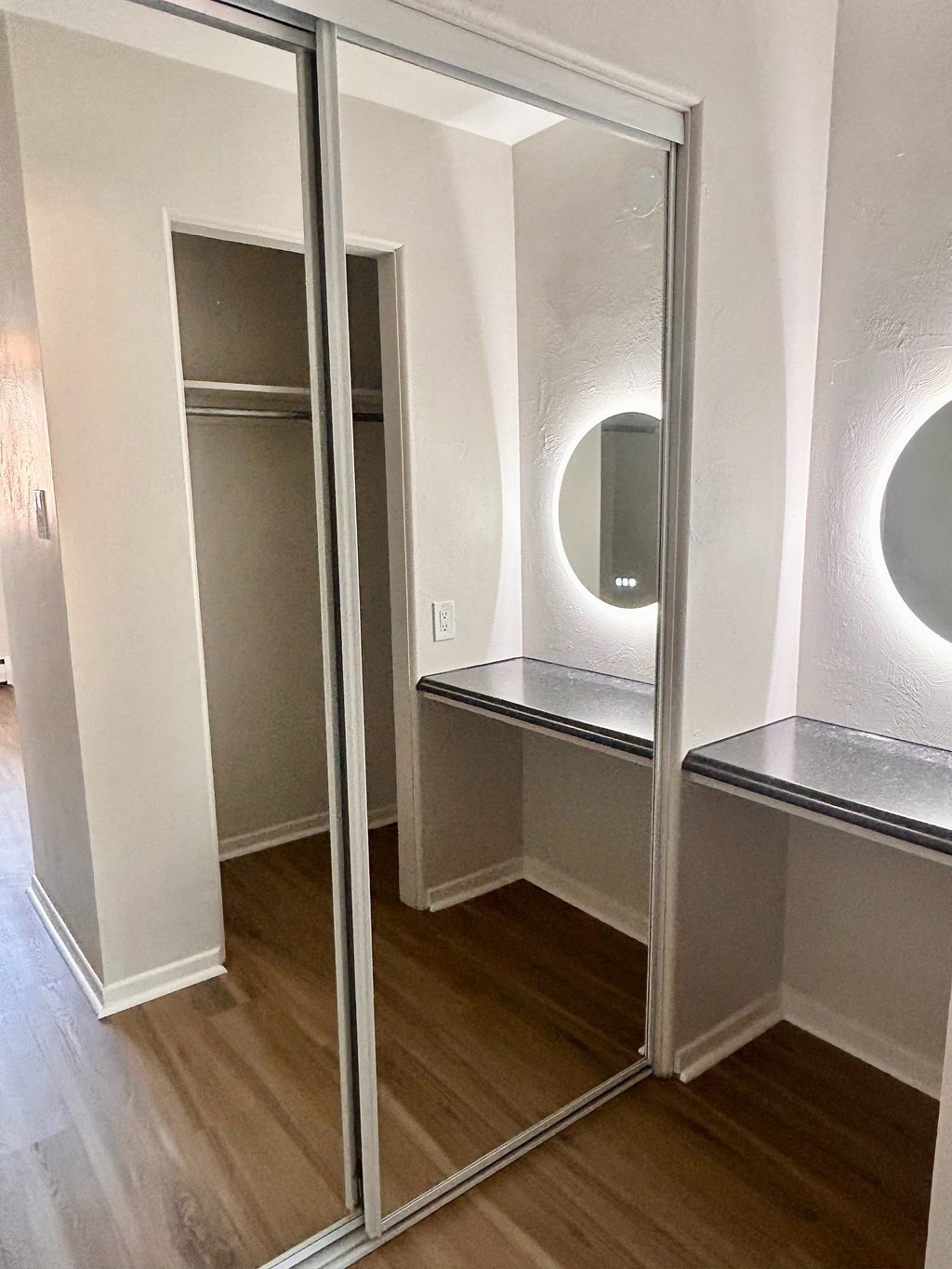 A white closet with a mirror and shelves.