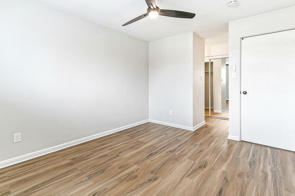 A room with a ceiling fan and wooden flooring.