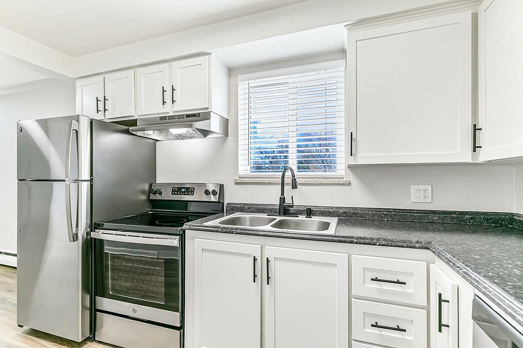 A kitchen with a stainless steel refrigerator and white cabinets.