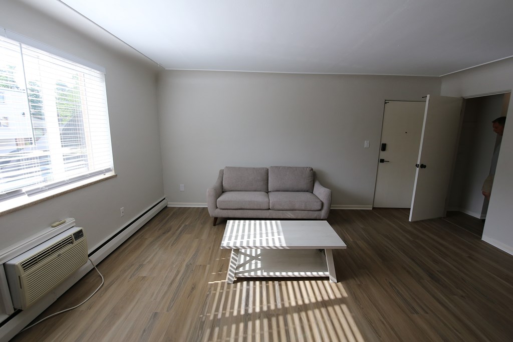 A living room with a couch, a coffee table, and a window with blinds.