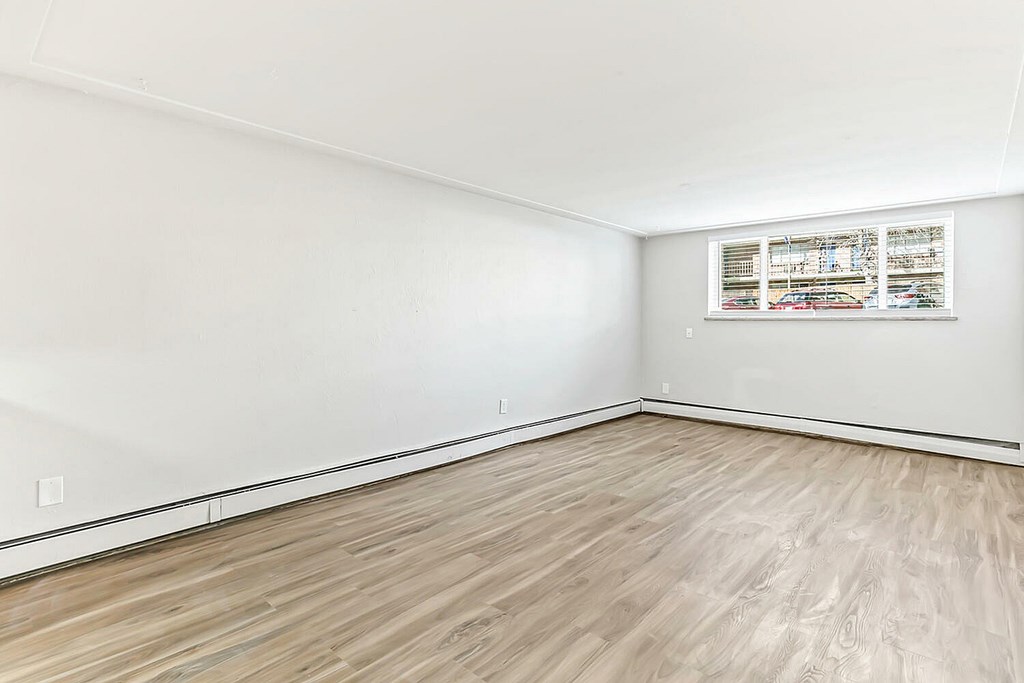 A room with wooden flooring and a window with blinds.