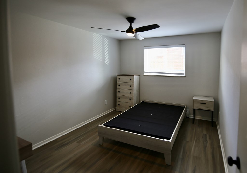 A bedroom with a bed, dresser, and window.