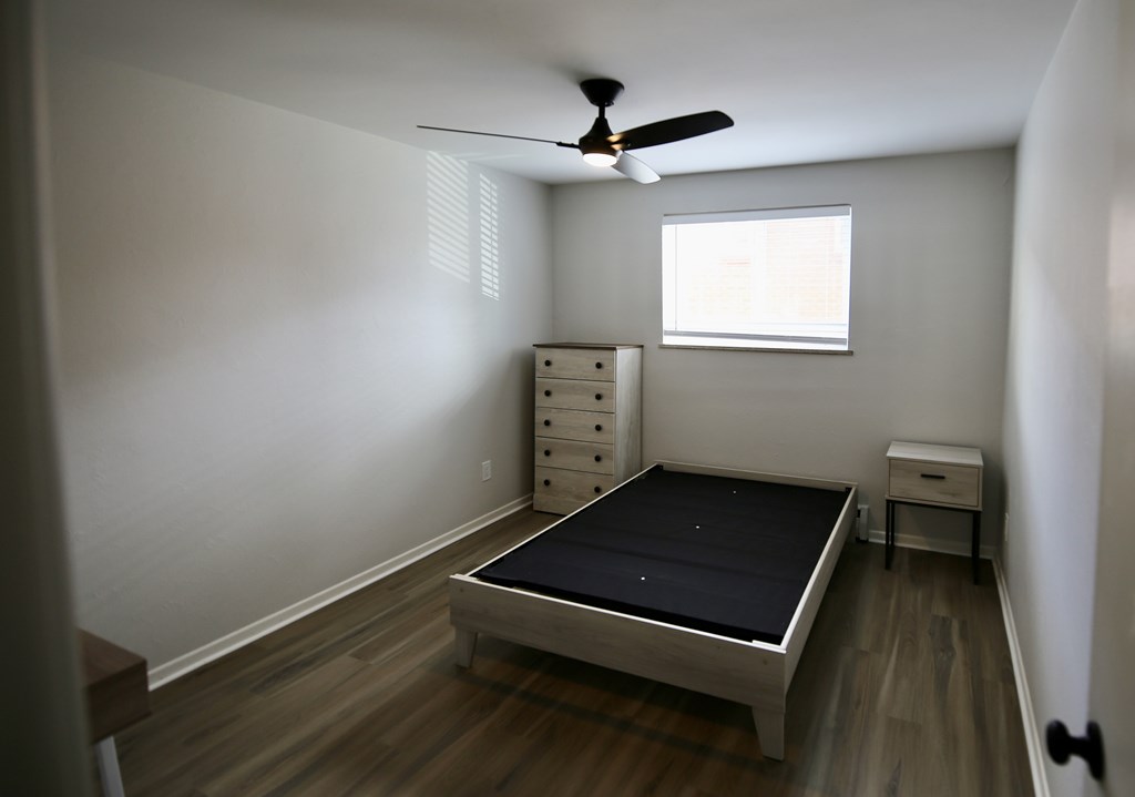 A bedroom with a bed, dresser, and window.