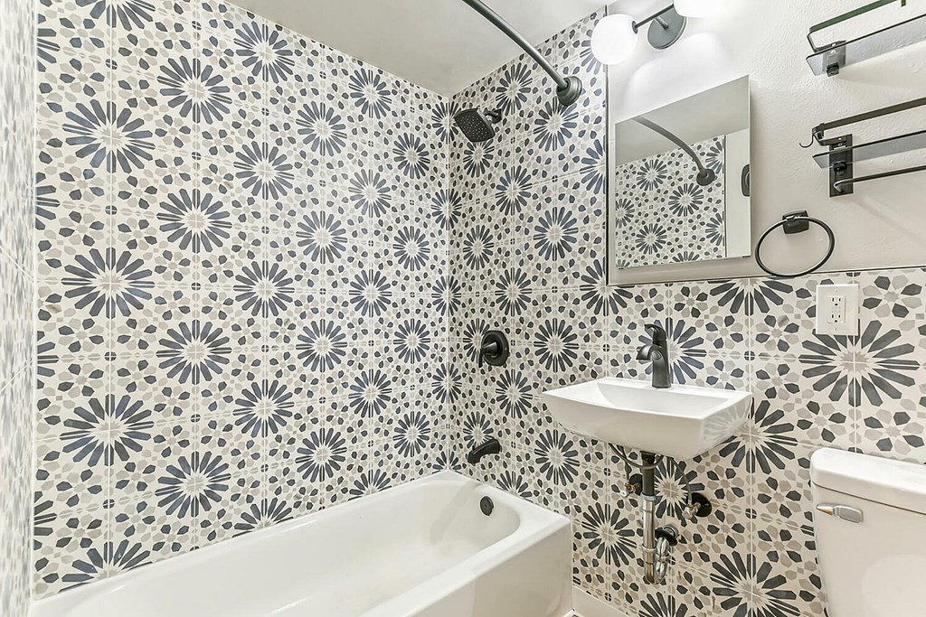 A bathroom with a patterned tile wall and a white sink.
