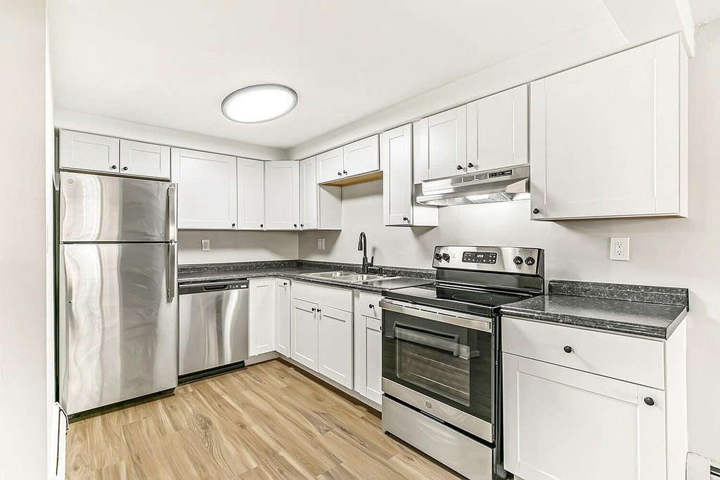 A modern kitchen with stainless steel appliances and wooden floors.
