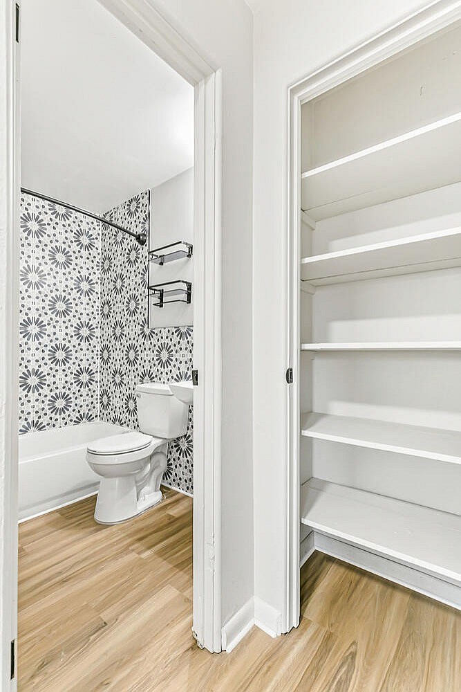 A white toilet is in a bathroom with a white cabinet.